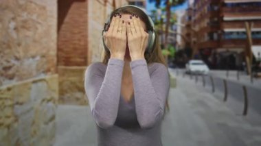 Kulaklık takan kadın şehir sokaklarında gri gömlekli, tırnakları boyalı, gülümseyen, sürpriz yapan, açık havada canlı şehir ortamında dikilen kadın..