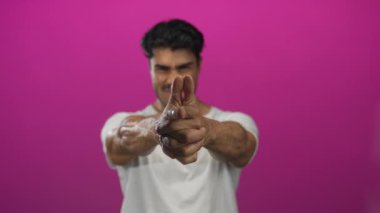 Parlak pembe stüdyoda gülümserken silah gibi uzanan eli sımsıkı ve parmaklarını uzatmış bir adam..