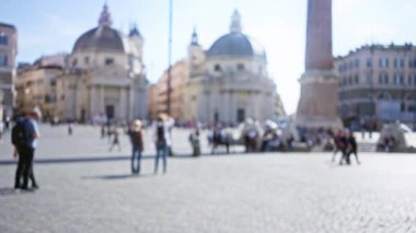 Roma, Piazza del Popolo 'daki kadın ve erkeklerin güneşli bir günde Bokeh etkisindeki ikonik mimariyle şehir yaşamını görüntüledikleri bulanık bir manzara..