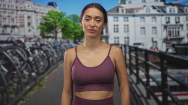 Amsterdam caddesindeki bir kadın, spor sutyeninde çıplak göbeğini gösteren el kaldırıyor. Kendine güvenen şehir sağlığı..