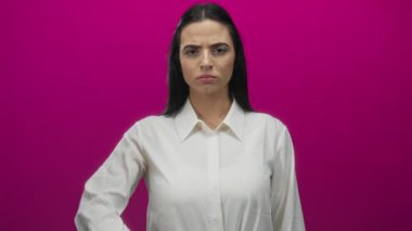 Canlı pembe duvarın önünde eli yüzü üzerinde duran bir kadın. Duygularını ve iç gözlemlerini kavramsal bir ortamda ifade ediyor. Beyaz gömlek giyiyor, gizem ve kimlik taşıyor..