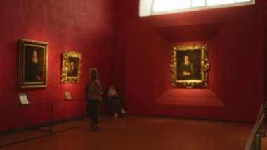 Odaklanmamış çerçeveli resimler, yumuşak bokeh ve sıcak pencere ışığı ile bulanık kırmızı müze galerisi içi; arkaplan telif alanı arka planı.