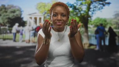 Canlı, güneşli yeşil parkta sessizlik için parmakları dudaklarına kadar uzanan genç Afro-Amerikalı kadın, sessizlik..