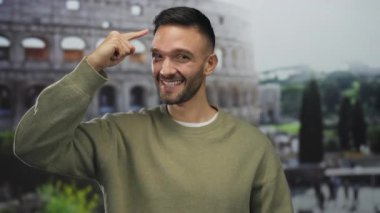 Roma 'nın ikonik kolezyumunun önünde gülümseyen ve kafasını gösteren İspanyol bir adam görkemli bir italyan simgesi gibi düşünceli bir duruş sergiliyor..