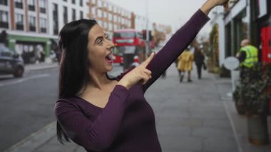 Kadın heyecan verici bir şekilde hareketli bir şehir caddesini işaret ediyor, canlı bir enerji ile, işaretler gösteriyor ve çevresindeki kentsel çevreyle meşgul oluyor..