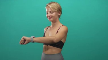 Stüdyoda spor sütyen ve tayt giyerken karın kaslarını ve karın kaslarını gösteren akıllı bakışları kontrol eden bir kadın..