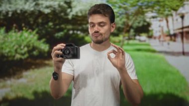 Elinde DSR kamera olan ve yeşil çimenli ve ağaçlı parkta 