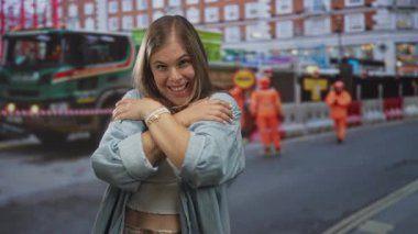 Gülümseyen kadın kollarını göğsünde gezdiriyor. Gün ışığında çıplak karnını gösteriyor. Kendini kabullenme..