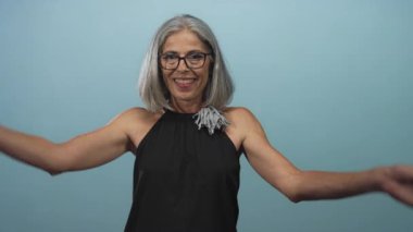 Kollarını kaldıran ve gülümseyen bir kadın. Stüdyoda yüzü donuk, kendine güveni tam bir kadın..