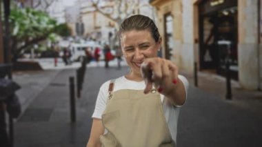 Orta yaşlı bir kadın gün ışığında gülerken elleri ile kalp şekli oluşturur..