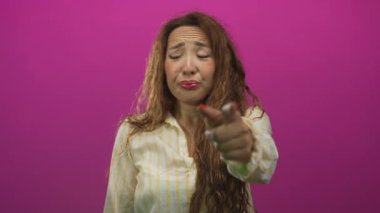 Genç, beyaz bir kadın pembe bir stüdyoda solu işaret ediyor. Etkileyici bir poz sırasında. Kovulma..