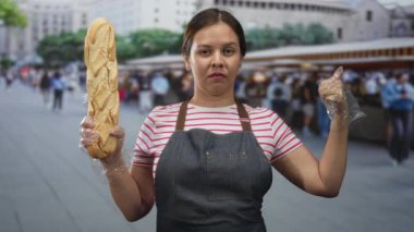 Eldivenli baget tutan ve sokak pazarında el hareketi yapan kadın; yerel girişimcilik kararlılığı.