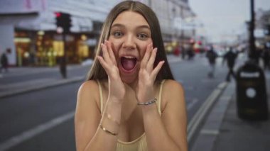 Gün ışığında, şehir caddesinde, ağzı açık, elleriyle suni teneffüs yapan genç bir kız. Sürpriz neşe beklentisi..