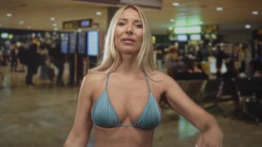 Sarışın kadın el ele tutuşup havaalanı terminalinde çıplak omzunu gösteriyor; beklenti yolculuğu.