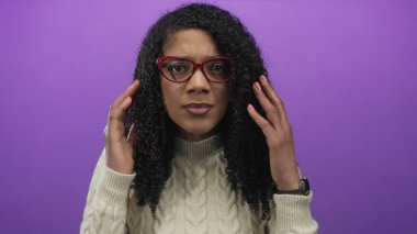 Kırmızı gözlük takan ve balıkçı yaka kazak giyen kadın, stüdyoda kıvırcık saç ve masaj tapınaklarını ayarlar; stres yorgunluğu hüsranı.