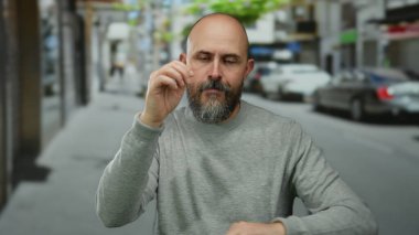 Sakallı kel adam hareketli bir şehir caddesinde enerjik bir şekilde dans ediyor, canlı açık hava atmosferini ve dinamik hareketleri yakalıyor..