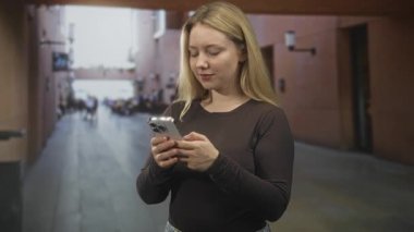 Akıllı telefonu tutan kadın, elleri görünür durumda ve havaalanı koridorunda ekrana bakıyor. Konsantrasyon bekliyor..