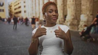 Afrika kökenli Amerikalı bir kadın, tarihi bir binanın ön cephesine el sallayarak el kol hareketi yapıyor..