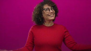 Kırmızı kazak giyen kadın kollarını kaldırır stüdyoda canlı mor arkaplan karşısında; neşe.