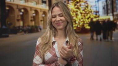 Sarışın kadın kalabalık bir Noel pazarında el ele tutuşuyor; sevinç minnettarlığı mutluluğu ısıtıyor.