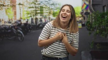 Yumruklarını sıkmış ve ellerini kaldırmış bir kadın sokakta gülümsüyor, neşe içinde ağzı açık; sevinç zaferi kutlaması.