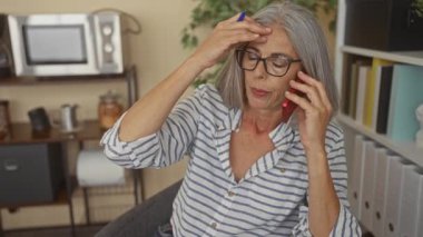 Ofis binasında kırmızı akıllı telefonu elinde tutan bir kadın, alnında mavi kalemle ofis binasının yakınında, mali kaygıları olan bir kağıt işçisi..