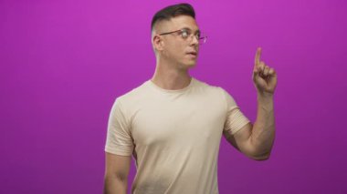 Mor bir stüdyoda baş parmağı ve kolu açık bir şekilde el hareketi gösteren bir adam sade arka plana karşı; onaylanmamış.