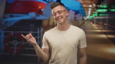 Gülümseyen ve Shaka hareketi yapan bir adam sol eli yolcu gemisinde bir can simidinin yanında; güven macerası.