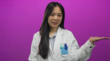 Üniformalı genç Çinli kadın bilim adamı izole edilmiş pembe arka plan duvarını teslim ediyor..