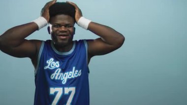 Stüdyoda elleri başında ve kolları kaslı bir adam mavi bir Los Angeles basketbol forması giyiyor. Hayal kırıklığı..
