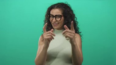 Yeşil bir stüdyoda gözlüklü ve gülümseyen bir kadın, özgüven teşviki.