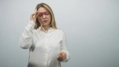Kadın kırmızı gözlük kaldırır ve düz bir stüdyoda beyaz gömlek giyerek burnunun köprüsünü çimdikler; stres giderici.