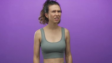 Kırışık kaşlı genç İspanyol kadın, elleri mor stüdyo ortamında olan tapınaklara baskı yapıyor..