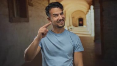 Mavi tişörtlü genç İspanyol, tarihi üniversite koridorunda dışarıda selam veriyor.
