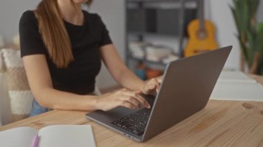 Ev stüdyosunda elleri klavyede dizüstü bilgisayarda yazan genç İspanyol kadın; konsantrasyon verimliliği.