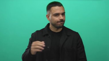 Canlı yeşil bir stüdyo duvarına karşı çapraz kollu siyah ceket giyen İspanyol genç adam reddedildi..