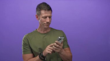 Akıllı telefonu dinleyen ve mor stüdyodaki kamerayı işaret eden adam; güven bağlantısı nişanı.