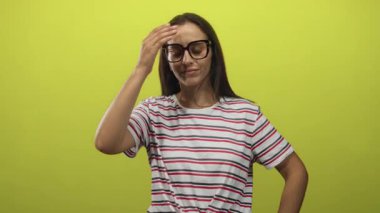 Alnında çizgili tişört ve limon yeşili stüdyo ortamında gözlük takan çıplak kol derisi ve kapalı gözler gösteren bir kadın..