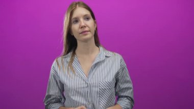 Stüdyoda ağzı açık, elleri sımsıkı bağlı, çizgili tişört giyen bir kadın sarı saç çerçeveli bir yüz gösteriyor..