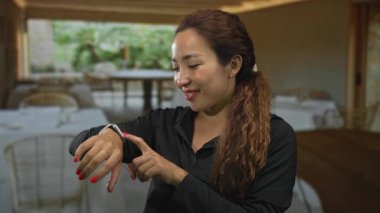 Bir restoran binasının içinde bileğindeki akıllı hareketi gösteren kadın parmağı; zaman kontrolü beklentisi.