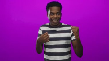 Mor stüdyoda gülümseyen bir adam çizgili gömlek giyer; zafer direnci motivasyon kararlılığı.