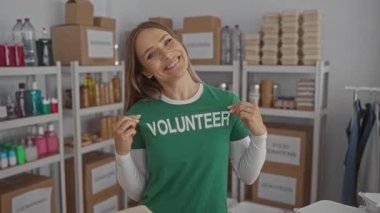 Bağış merkezinde gülümseyen bir kadın gönüllü gömleği giyip evin içinde kutular ve malzemelerle çevrili bir şekilde hayır kurumunun mekanında olumlu ve yararlı bir atmosfer yakalamış.