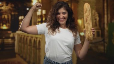 Kadın gülümseyen ve kameraya bakan bir kilise binasında kol ve baget tutuyor. Gurur gücü..