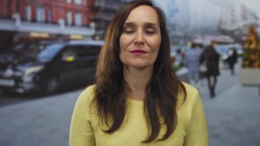 Latin kökenli genç bir kadın şehir sokaklarında dudaklarıyla öpüşüyor..