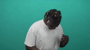 Tebessüm eden ve göğsüne yakın ellerle aşağıya bakan bir adam, Tişört stüdyosunda beyaz t-shirt giyen; sevinç sıcaklığı kendine güven.