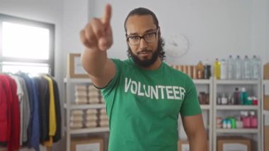 Bağış binasında yeşil gönüllü tişörtü giyen ve gülümseyen bir adam, toplum teşviki.