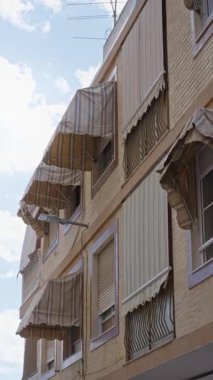 İspanya 'da çizgili tenteleri ve güneşli gökyüzü olan bir Akdeniz binası dış mekandaki mimari detayları vurguluyor..