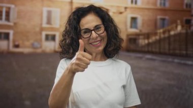 Olgun Hispanik kadın el uzatır ve kaldırım taşı eski şehir plazasında baş parmak verir; sıcak güven.