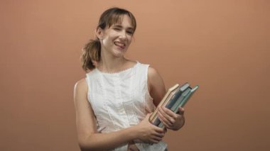 Şeftali atölyesinde beyaz bluz giyerken elleri açık, dili açık ve gülümseyen bir kadın..