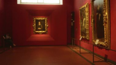 Sığ bokeh arka planı ve yumuşak odaklı tabloları olan bir müzede bulanık kırmızı galeri içi; arka plan şablonu sakin.